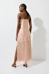 Falda midi color rosado, confeccionada en tejido fluido de satén con cremallera lateral oculta. Presenta un bajo festoneado de encaje y abertura pronunciada en un lateral.