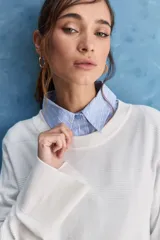Sweater blanco de punto con diseño holgado, cuello redondo, mangas largas acampanadas y detalles de textura horizontal en el tejido.