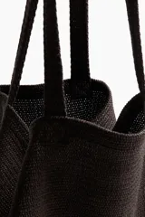 Bolso de playa color marrón, tipo tote, confeccionado en tejido texturizado con dos asas superiores.