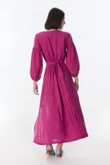 Vestido midi fucsia de lino, con escote en V, mangas largas abullonadas, lazos frontales y tajo lateral.
