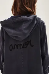 Campera tipo parka de canvas color azul marino, con capucha, cierre frontal y bolsillos laterales. Presenta un bordado en hilo rojo en la parte inferior frontal con la frase 'She's Electric'.