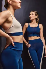 Top deportivo color beige con contorno inferior y tiras cruzadas en la espalda color borgoña. Cuenta con almohadillas removibles.