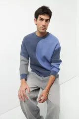 Sweater de punto con diseño geométrico en tres tonos de azul y gris, de cuello redondo y manga larga.