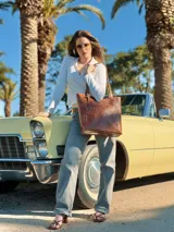 Bolso shopper de cuero color marrón con asas al hombro y dije colgante en forma de búho.