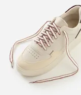 Championes casuales Satinato de diseño urbano, confeccionados en poliuretano con recortes superpuestos y costuras visibles. Presentan puntera redondeada con microperforaciones, suela alta de goma, refuerzo trasero en color contrastante y cordones con diseño diferenciado.