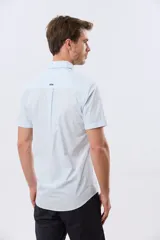 Camisa lisa de algodón azul marino, de manga corta, con cuello camisero, cierre frontal de botones y un bolsillo aplicado en el pecho.