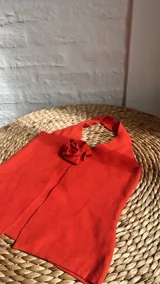 Top rojo con cuello halter y detalle de rosa en el centro.