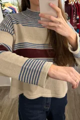 Sweater de punto corto con diseño a rayas horizontales en tonos beige, azul y bordó, cuello redondo y mangas largas con hombros caídos.