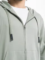 Campera de felpa con cierre frontal metálico, capucha con cordones ajustables y bolsillos tipo canguro. Presenta puños y ruedo acanalados.