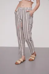 Pantalón babucha celeste con rayas verticales blancas, cintura elástica con cordón y detalle de borlas.