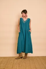 Vestido largo color verde petróleo con escote en V, detalles de bordado metálico en el escote y bolsillos laterales.