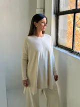 Sweater de punto color crudo, con cuello redondo, manga larga y diseño holgado con costura central vertical.