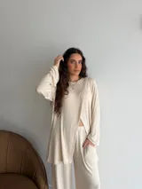 Conjunto de dos piezas color gris melange, confeccionado en tela de lanilla, compuesto por un buzo de manga larga con diseño cruzado al frente y un pantalón largo de corte holgado y tiro alto.