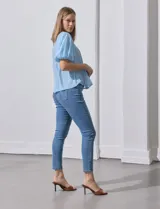 Blusa blanca de gasa marca Zac & Rachel, con frunces en la parte delantera, mangas cortas con puño elastizado, abertura central en la espalda y botón.