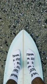 Pack de dos pares de medias blancas con texto 'Glassy Waves' estampado en negro.