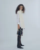 Chaleco largo de punto trenzado color gris con cuello alto y cierre frontal con cremallera metálica.