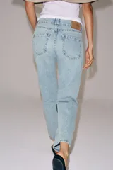 Jeans de tiro medio con corte slim leg, confeccionados en denim de lavado claro. Presentan diseño clásico de cinco bolsillos, cierre frontal con cremallera y botón, y cintura con trabillas.