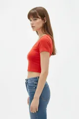 Top cropped de algodón blanco, al cuerpo, con mangas cortas y escote redondo amplio.