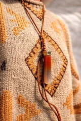 Collar con cordón de cuero y dije alargado de piedra verde con detalles translúcidos y casquillo metálico dorado.