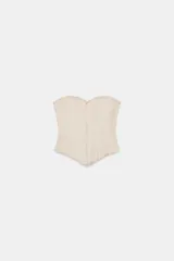 Top estilo corset de escote corazón y hombros descubiertos, con varillas interiores para estructura. Presenta cierre frontal con ganchos metálicos y ajuste en la espalda mediante cordones cruzados.