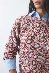 Sweater de punto con diseño de estampado animal print abstracto en tonos tierra y azul claro. Presenta cuello redondo a la base, mangas largas levemente amplias y terminaciones acanaladas en puños y ruedo.