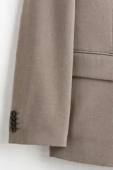 Blazer cruzado de tejido suave color beige/topo, con solapas de pico, ojal decorativo y cierre de doble botonadura. Posee bolsillo superior insertado, dos bolsillos delanteros ribeteados con solapa y botones decorativos en los puños.