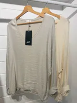 Blusa color crema con lentejuelas, de mangas largas y escote redondo.