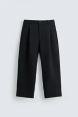 Pantalón de corte relajado con pliegues frontales, bolsillos laterales y bolsillos traseros de vivo. Cuenta con cierre frontal de cremallera y botón.