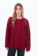 Buzo tejido de punto con diseño de trenzas, color negro, de corte holgado, cuello redondo y mangas largas.