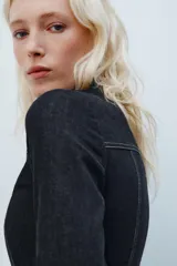 Camisa de denim negra con cuello solapa, manga larga, pespuntes a contraste y cierre frontal con cremallera metálica.