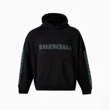 Hoodie Balenciaga de corte oversize, color negro con efecto desgastado. Presenta el logo de la marca estampado en estilo stencil en el pecho y en ambas mangas, con capucha y bolsillo frontal tipo canguro.