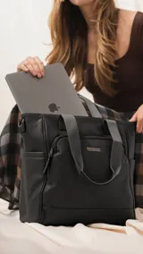 Cartera tipo tote marrón de diseño práctico y versátil, confeccionada en símil cuero con textura granulada. Cuenta con asas cortas fijas, bolsillos exteriores con cierre al frente y atrás, y bolsillos laterales abiertos. Su interior es amplio e incluye bolsillos organizadores. Viene con una correa ajustable y desmontable.