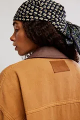 Campera oversize de denim en color marrón, con hombro caído, cuello de lona marrón en contraste, bolsillos frontales con solapa, cierre de botones metálicos y puños abotonados.