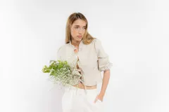 Blusa corta blanca de lino con mangas 3/4 abullonadas, escote en V con volados y cierre con lazos.