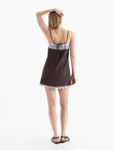 Vestido corto blanco de tirantes finos, con escote en V y detalles de encaje en el escote y el ruedo, con tajo lateral.