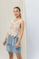 Top tejido artesanal color crudo, confeccionado en punto calado con diseño protagonista. De silueta recta y calce relajado, presenta escote amplio y terminación inferior con flecos.