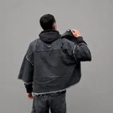Chaqueta de denim negro con lavado ácido, cuello mao, mangas cortas, cierre frontal con botones metálicos y un bolsillo aplicado en el pecho. Presenta detalles de terminaciones desflecadas en el cuello, mangas y ruedo.