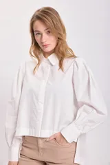 Camisa blanca de mangas largas con hombreras y cuello clásico.