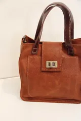 Cartera marrón de cuero con doble asa corta y cierre con solapa y broche metálico.