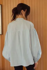 Camisa celeste con cuello mao y mangas abullonadas.