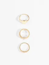 Set de tres anillos dorados con diferentes diseños: uno con forma de sello, otro con textura y uno con pequeños detalles geométricos.