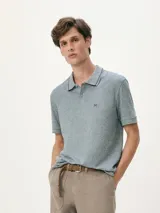 Polo de hombre color gris oscuro jaspeado, con cuello y puños de manga con ribete negro. Presenta un pequeño logo bordado en el pecho.