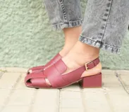 Sandalia de cuero color bordó con diseño de tiras anchas entrecruzadas, punta cuadrada y talón descubierto con pulsera ajustable. Cuenta con taco ancho medio forrado en cuero.