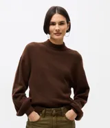 Suéter de punto color marrón chocolate, con cuello alto y mangas largas con puños ajustados. Presenta un diseño de corte corto y holgado.