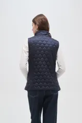 Chaleco acolchado negro con diseño de costuras geométricas, cierre frontal completo y bolsillos laterales.
