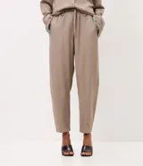 Pantalón carrot de viscolino color marrón, de corte amplio en la cadera y ajustado hacia los tobillos. Cuenta con cintura elástica en la parte posterior, lazo frontal para ajuste y caída liviana.