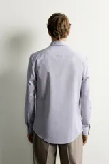 Camisa de corte slim fit con estampado de rayas verticales finas, cuello italiano, manga larga con puños abotonados y cierre frontal de botones.