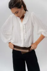 Camisa de manga larga color beige con diseño a rayas sutiles, cuello mao con volados y abertura frontal con detalles de volados a un lado.