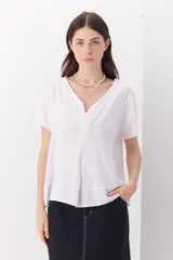 Blusa blanca de lino con escote en V, mangas cortas y corte holgado.