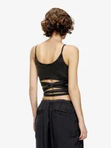 Top corto negro con efecto lavado, tirantes finos y escote recto. Presenta una tira larga de tela que se anuda alrededor de la cintura a modo de fajín o cinturón.